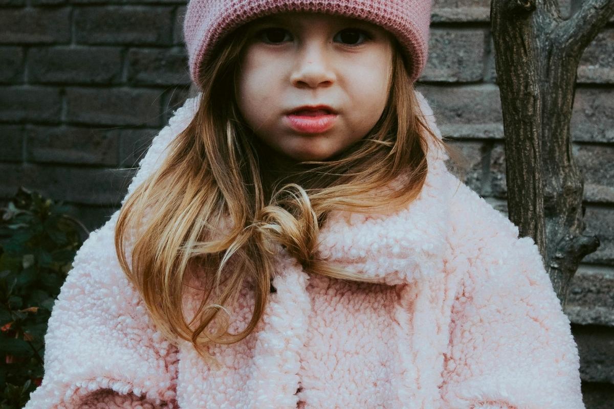 Child wearing a furry pink winter coat symbolizing lavish love of a gift from a mother